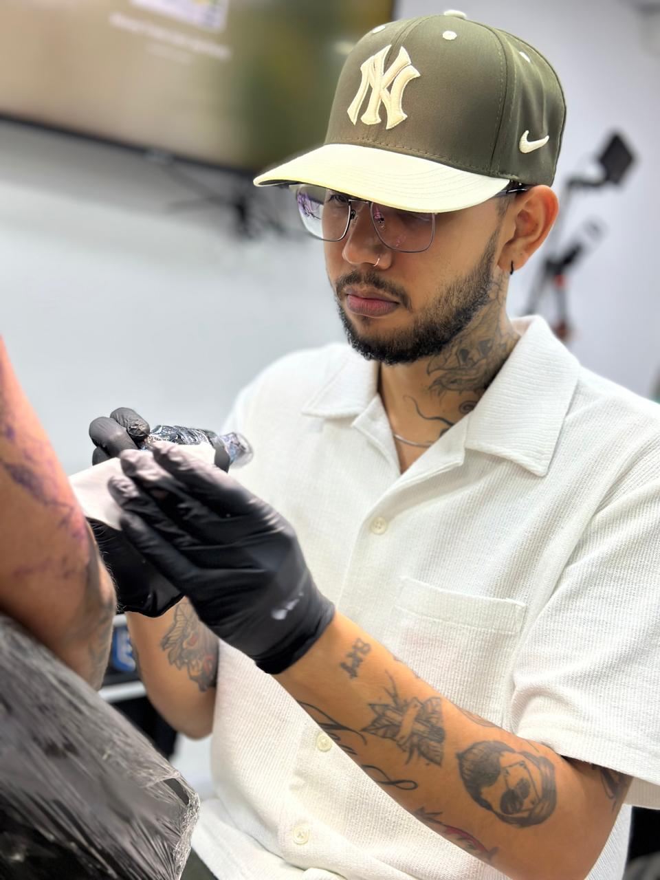 Fernando González tatuando en el estudio, con guantes y máquina en mano
